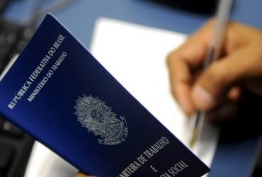 Imagem de uma carteira de trabalho sendo assinada.