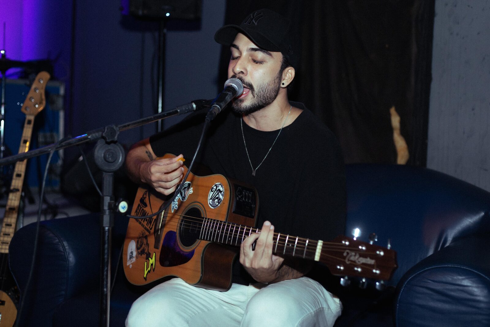 Conato de blusa preta com o violão e um microfone