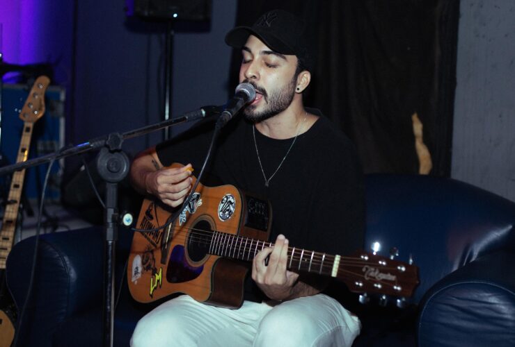 Conato de blusa preta com o violão e um microfone