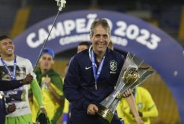 Homem de cabelo grisalho com uma roupa azul e segurando uma taça prata com detalhes dourados