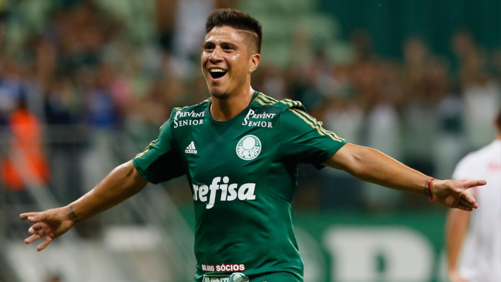 Jogador de futebol de camisa verde comemorando um gol