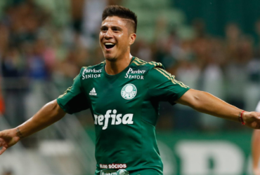Jogador de futebol de camisa verde comemorando um gol