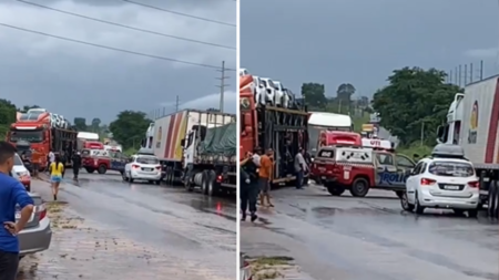 Rodovia com pista molhada cheia de veículos e viaturas da Polícia Militar