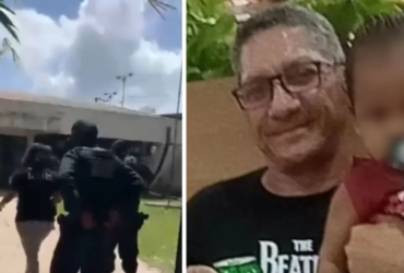 Homem de camisa preta segurando uma criança de colo