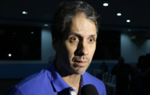 Homem de blusa azul dando entrevista
