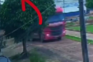 Caminhão vermelho derrubando um poste de energia