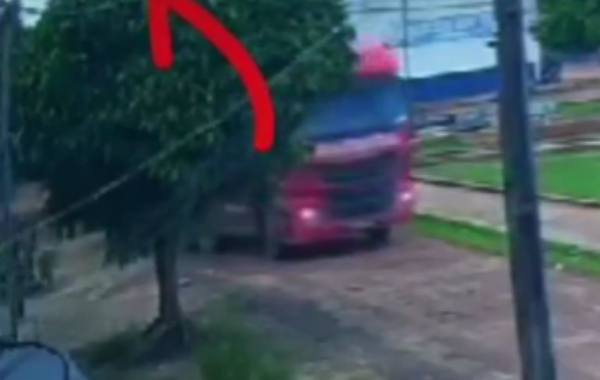 Caminhão vermelho derrubando um poste de energia