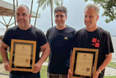 Três homens brancos segurando um quadro