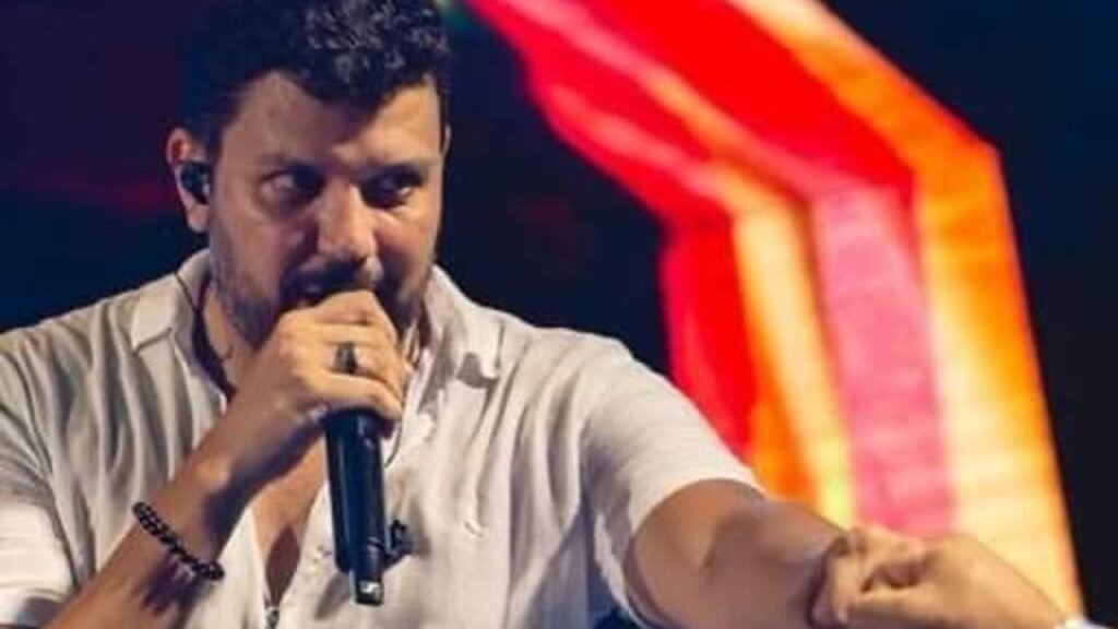 Cantor de pagode com um microfone na mão e apontando para algum lugar da plateia