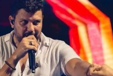 Cantor de pagode com um microfone na mão e apontando para algum lugar da plateia