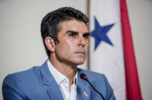 O governador do Pará, Helder Barbalho em foto com a bandeira do Pará ao fundo.