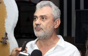 Medico de cabelo e barba grisalhos sendo entrevistado