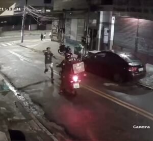 Via escura com um carro ao lado de uma moto