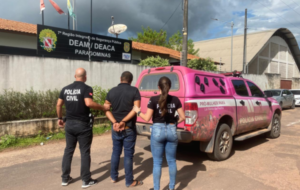 Homem e dois policiais em frente a Delegacia de Paragominas.