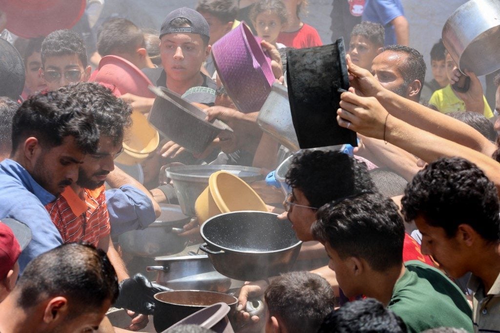 Palestinos disputam pequenas porções de comida em Gaza, devastada pela guerra e pelo bloqueio israelense.