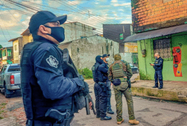 Policiais armados participam de operação em área urbana de Belém (PA), durante ação integrada de combate a facções criminosas. Na imagem, agentes da Polícia Civil e unidades táticas conversam diante de uma residência enquanto monitoram o entorno de uma rua residencial.