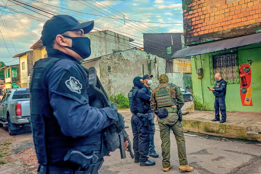 Policiais armados participam de operação em área urbana de Belém (PA), durante ação integrada de combate a facções criminosas. Na imagem, agentes da Polícia Civil e unidades táticas conversam diante de uma residência enquanto monitoram o entorno de uma rua residencial.