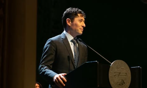 Prefeito de Minneapolis, Jacob Frey, sorrindo sutilmente em um pulpito