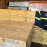 Apresentação da carda de uísque apreendida. As garrafas estão dentro de caixotes de madeiras, por cima deles um colete da Sefa-PA