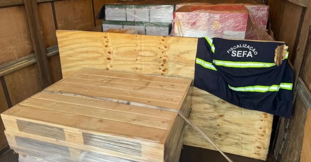 Apresentação da carda de uísque apreendida. As garrafas estão dentro de caixotes de madeiras, por cima deles um colete da Sefa-PA