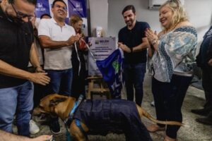 Prefeito Igor Normando tira pano da placa de inauguração do novo hospital veterinário. Na foto, estão outras pessoas e um cachorro