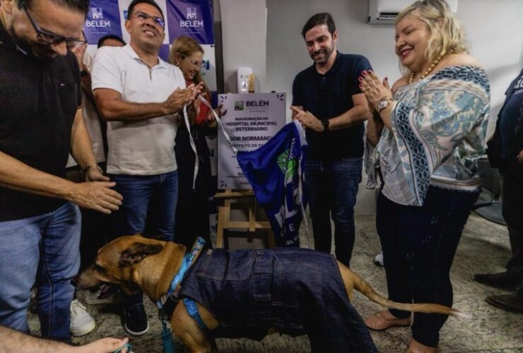 Prefeito Igor Normando tira pano da placa de inauguração do novo hospital veterinário. Na foto, estão outras pessoas e um cachorro