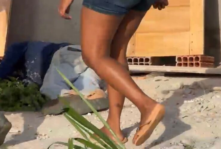 Homem caído ao chão depois de levar tiros. Mulher em pé olhando ele caído