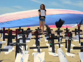 Na praia, cruzes aparencem enterradas na areia em sinal de protesto pela morte de passoas trans