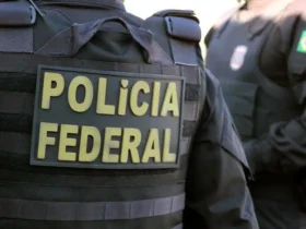 Dois policiais da Polícia Federal usando coletes, em um deles se lê “Polícia Federal”, em imagem em close.