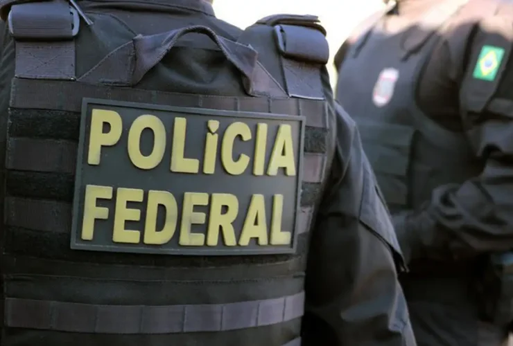 Dois policiais da Polícia Federal usando coletes, em um deles se lê “Polícia Federal”, em imagem em close.
