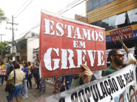 a imagem mostra manifestantes nas ruas com cartazes dizendo que estão em greve
