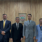 Autoridades da Polícia Civil e da Polícia Federal durante assinatura de acordo de cooperação, reunidas em sala com mesa e bandeiras ao fundo.