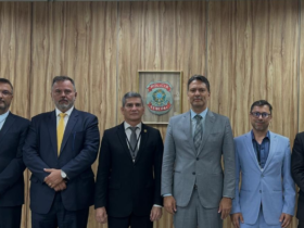 Autoridades da Polícia Civil e da Polícia Federal durante assinatura de acordo de cooperação, reunidas em sala com mesa e bandeiras ao fundo.