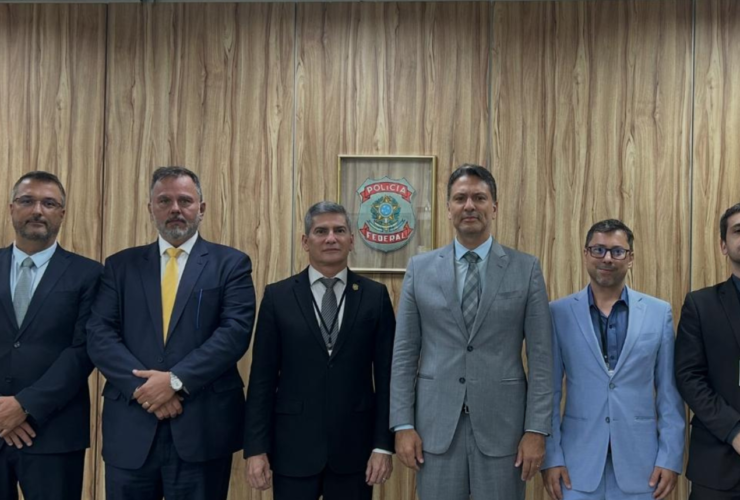 Autoridades da Polícia Civil e da Polícia Federal durante assinatura de acordo de cooperação, reunidas em sala com mesa e bandeiras ao fundo.