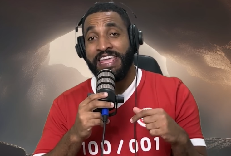 Humorista em vídeo para canal no YouTube usando fones de ouvido e segurando microfone, diante de cenário com fundo artificial que imita o céu.