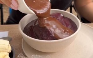 Tigeçla branca com açaí e chocolate sendo derramado por cima