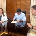 No centro da mesa, o governador Helder Barbalho assina um documento; à direita de Helder, está sentada a vice-governadora Hana Ghassan. À esquerda do governador, está sentado o presidente da ALEPA, o deputado Chicão.