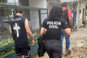Imagem do suspeito sendo conduzido por agentes da Polícia Civil até a delegacia.