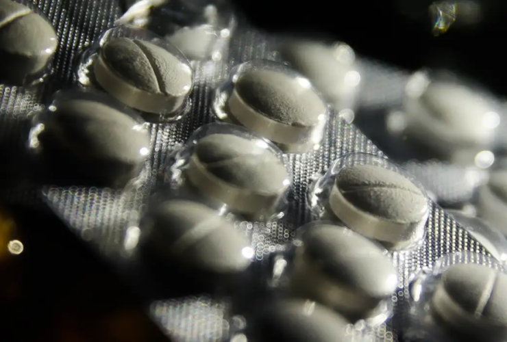 Imagem em close de uma cartela de pílulas de remédios brancos.