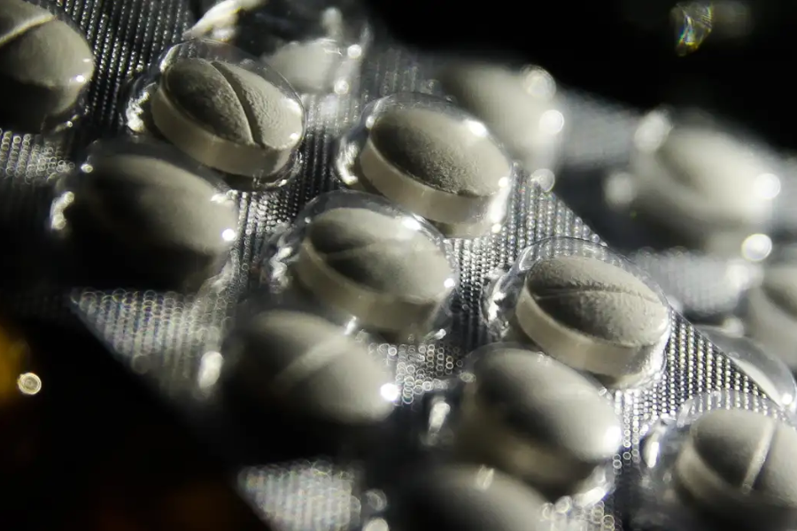 Imagem em close de uma cartela de pílulas de remédios brancos.