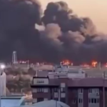 Imagem do ataque de mísseis no Aeroporto Mehrabad em Teerã, na capital do Irã. A imagem distante mostra o aeroporto em chamas com uma enorme fumaça preta no céu e prédios ao fundo.