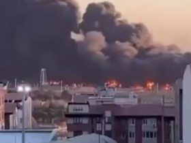 Imagem do ataque de mísseis no Aeroporto Mehrabad em Teerã, na capital do Irã. A imagem distante mostra o aeroporto em chamas com uma enorme fumaça preta no céu e prédios ao fundo.