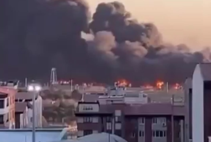 Imagem do ataque de mísseis no Aeroporto Mehrabad em Teerã, na capital do Irã. A imagem distante mostra o aeroporto em chamas com uma enorme fumaça preta no céu e prédios ao fundo.
