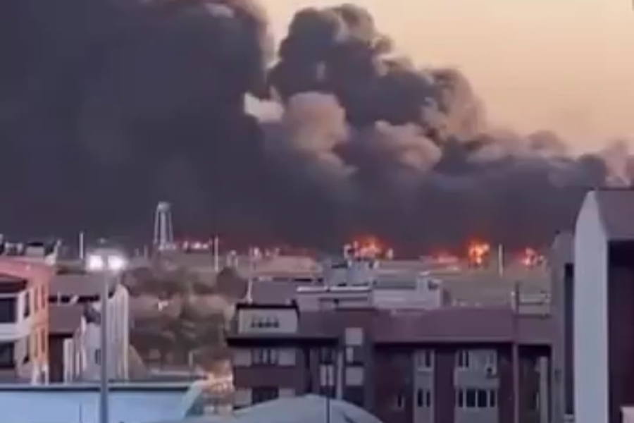 Imagem do ataque de mísseis no Aeroporto Mehrabad em Teerã, na capital do Irã. A imagem distante mostra o aeroporto em chamas com uma enorme fumaça preta no céu e prédios ao fundo.
