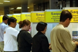 Na imagem aparecem várias pessoas realizando saques em caixas do Banco do Brasil.