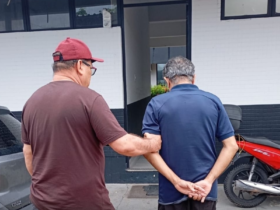 Imagem de um agente da Polícia Civil sem farda conduzindo o suspeito até a delegacia.