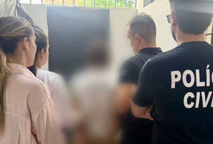 Na imagem aparece agentes da polícia civil deslocando o suspeito, sendo duas agentes mulheres e dois homens fardados. A imagem do suspeito aparece borrada.