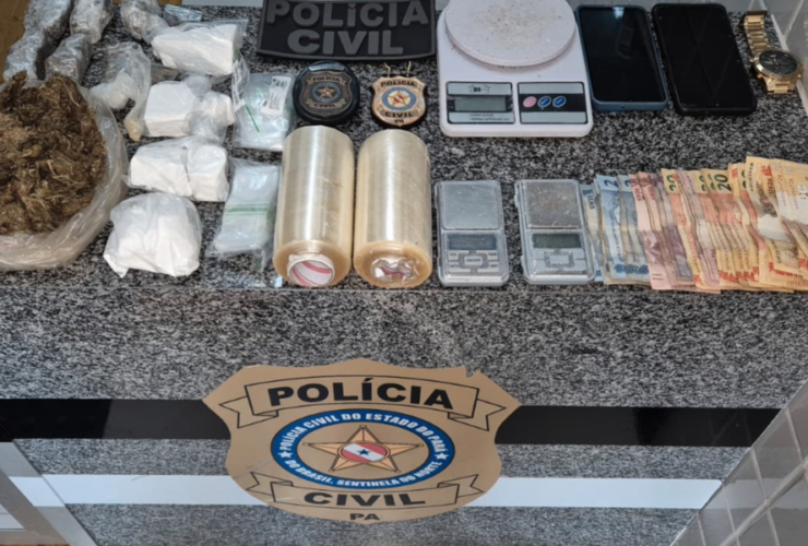 Na imagem aparece as apreensões sobre uma mesa de mármore, nela estão balaças de precisão, quantia em dinheiro, 2 rolos de plástico filme, drogas, além do selo da polícia civil.