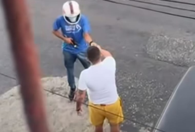 Na imagem o suspeito usando capacete e armado aborda a vítima no meio da rua.