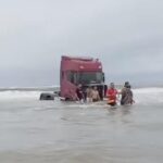 Caminhão atolado na água do mar.